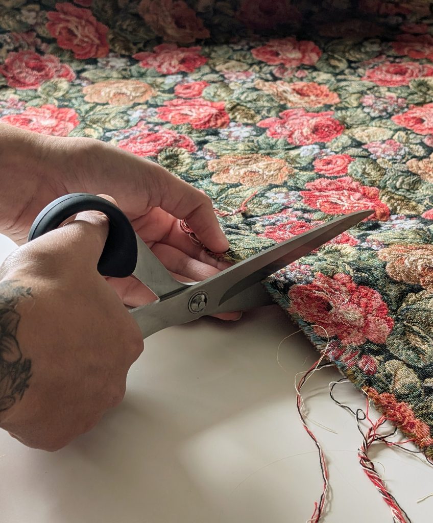 Découpe artisanale d'un tissu fleuri aux ciseaux dans l'atelier de couture O Fil d'Angèle.